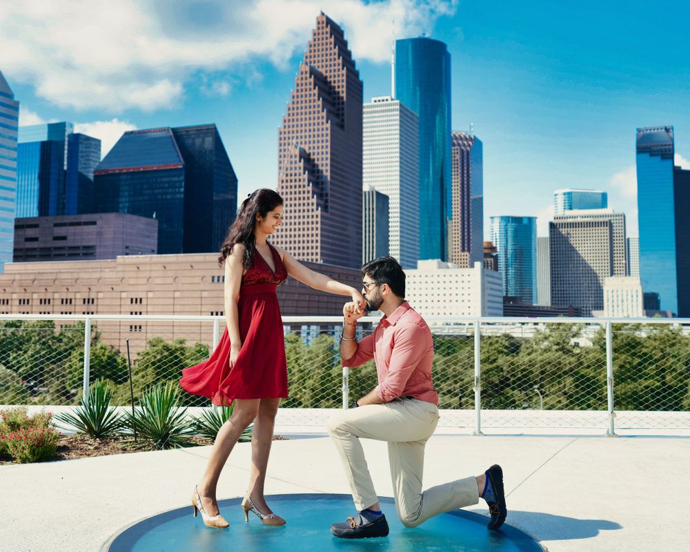 A romantic proposal moment against the Houston skyline with a couple on a blue circular platform.