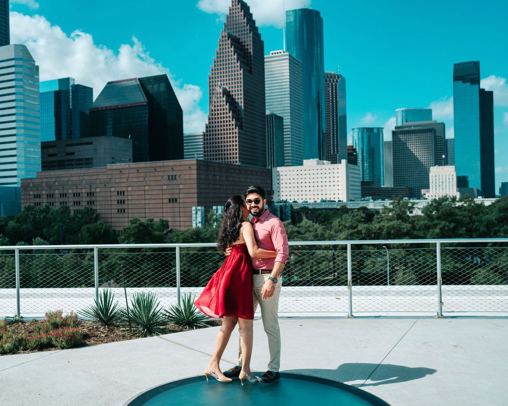 A couple embraces on a rooftop terrace with Houston's distinctive skyline in the background.