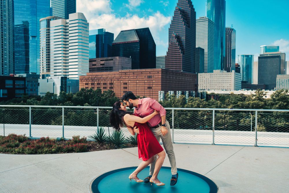 A romantic couple embrace on a blue circular platform with Houston's downtown skyline behind them.