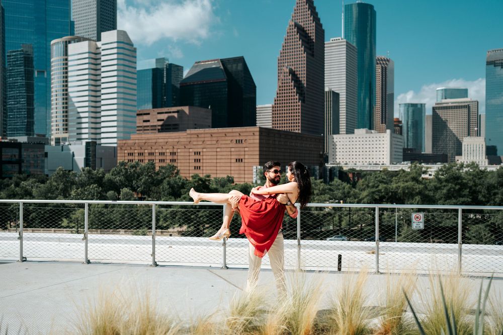 A dancer in red performs against the Houston skyline backdrop on an outdoor terrace with ornamental grasses.