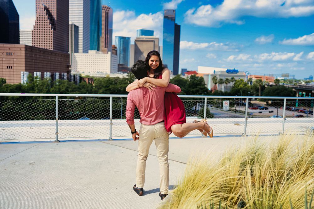 A couple poses romantically with the Houston skyline and city buildings in the background.