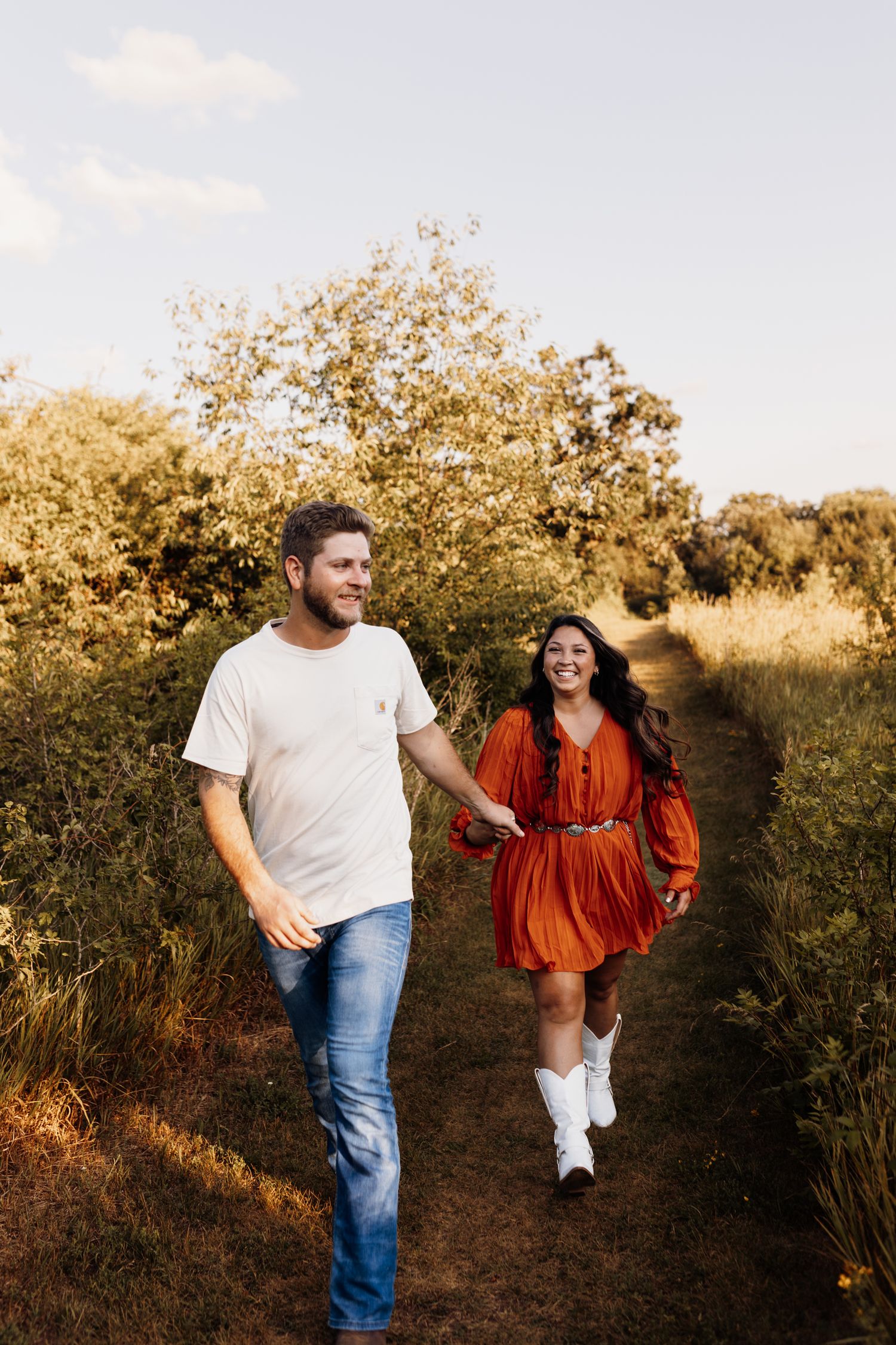 Couple walking and laughing together on a trail during sunset.