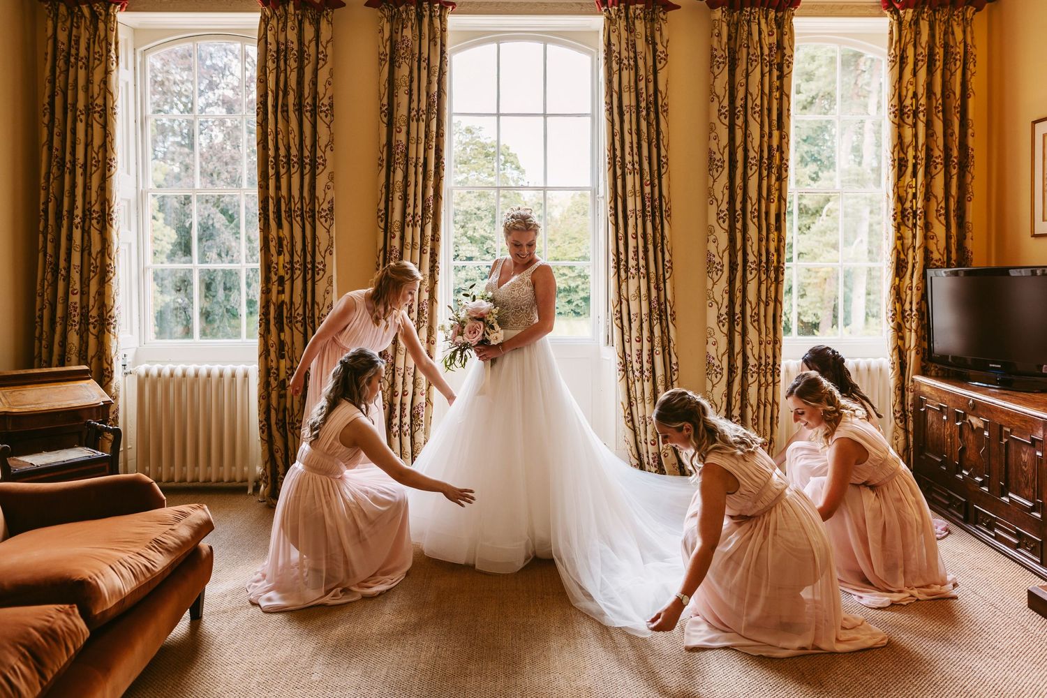 Ardington House Wedding photographer Vicky Lewis bride getting dress arranged surrounded by bridesmaids