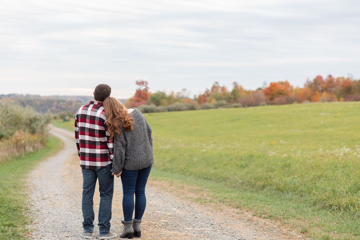 Romantic couple strolling hand in hand along a winding country path during autumn.