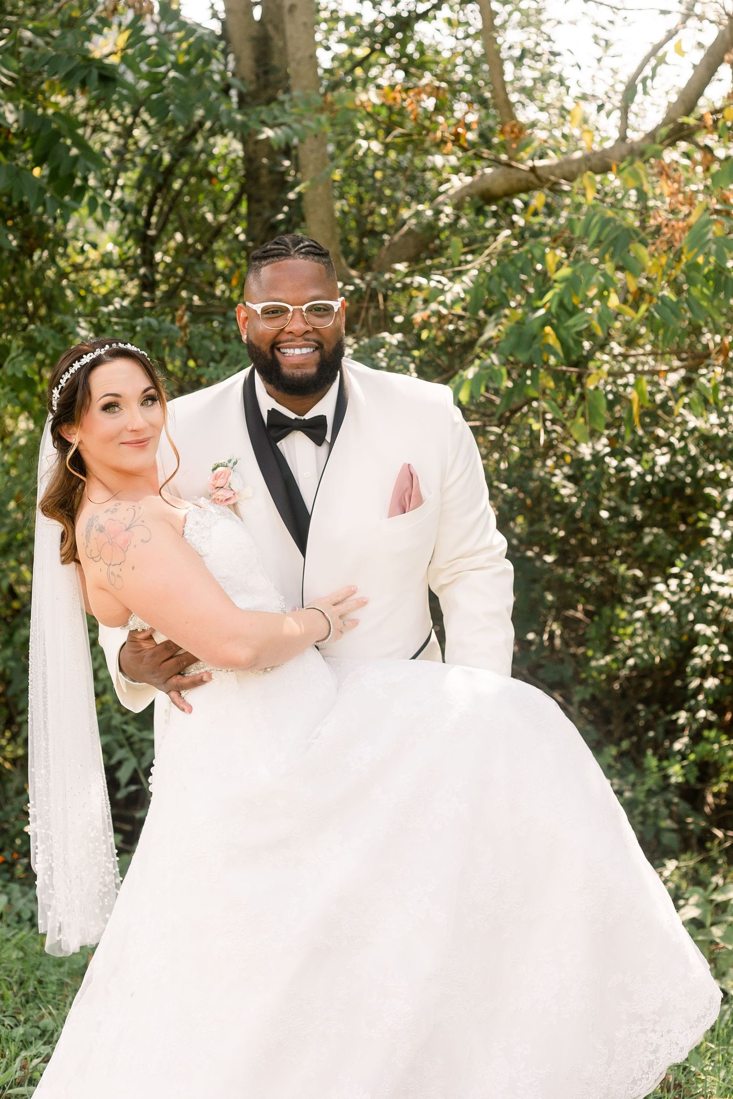 Joyful wedding couple posing playfully outdoors with white dress and suit.