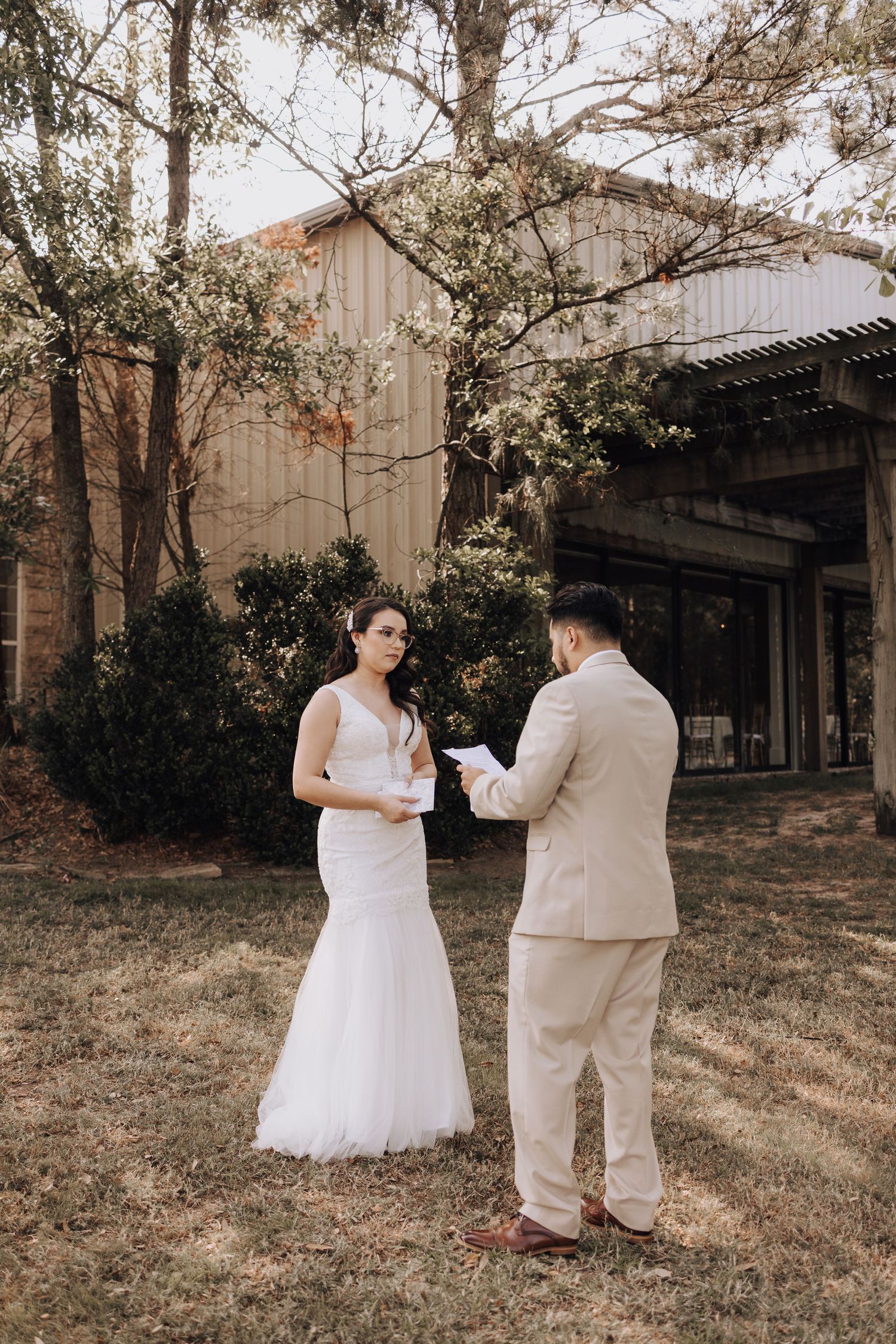 Couple exchanging vows in front of wooden building during intimate outdoor ceremony.