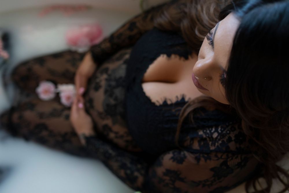 Dramatic black lace maternity boudoir photography with moody lighting.