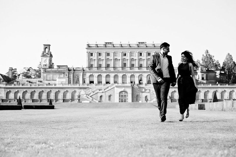 Couple walks along grand classical architecture building in black and white photograph.
