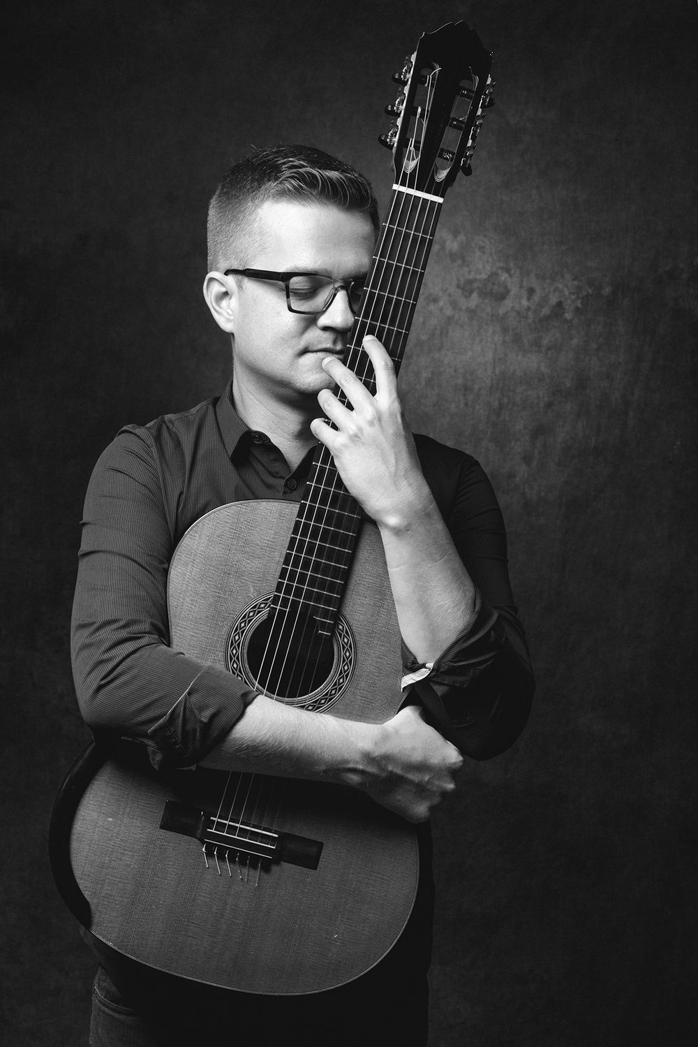 portret van een gitarist die de gitaar omhelst in de fotostudio