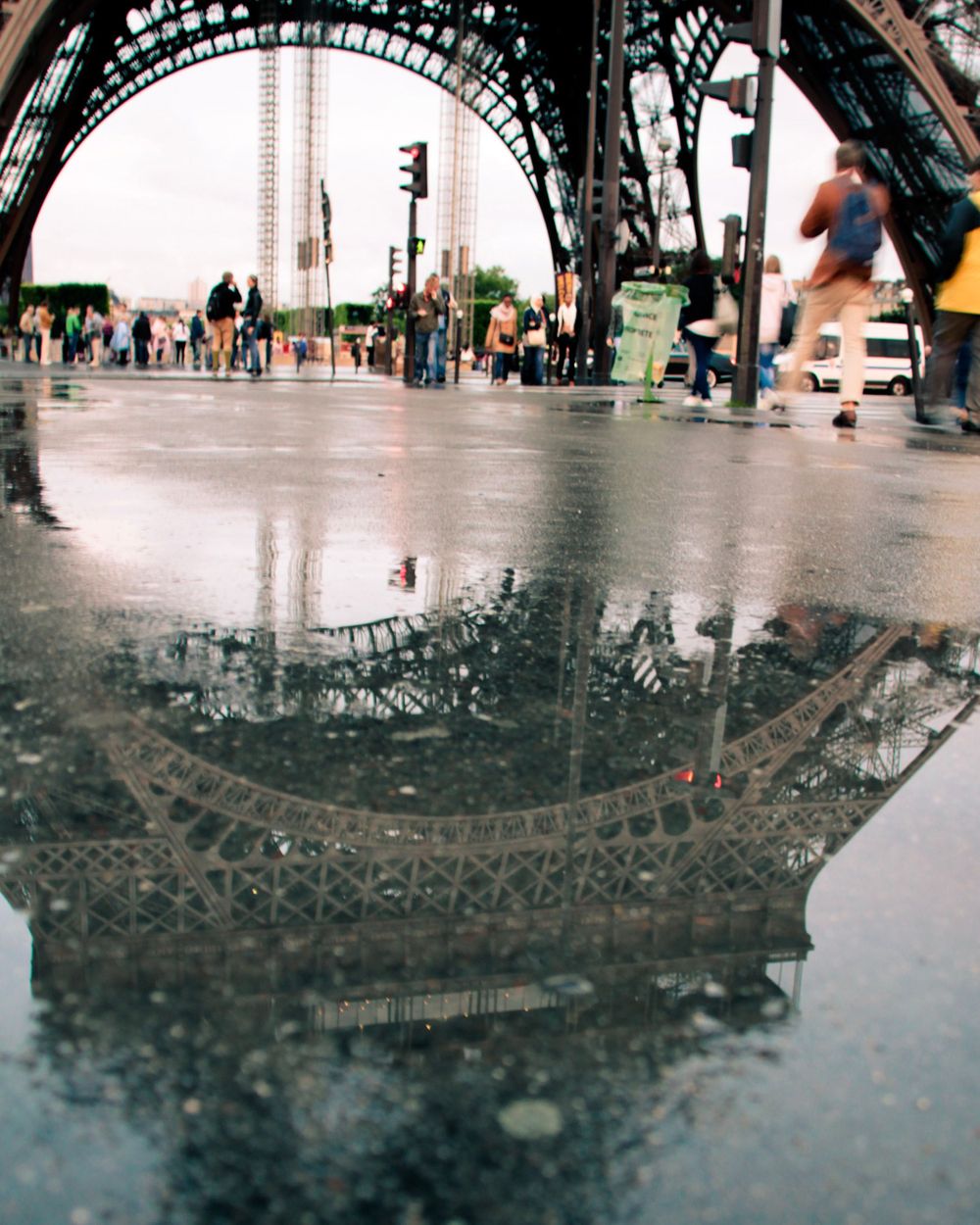 Puddle reflection of the Eiffel Tower base on a rainy day in Paris.