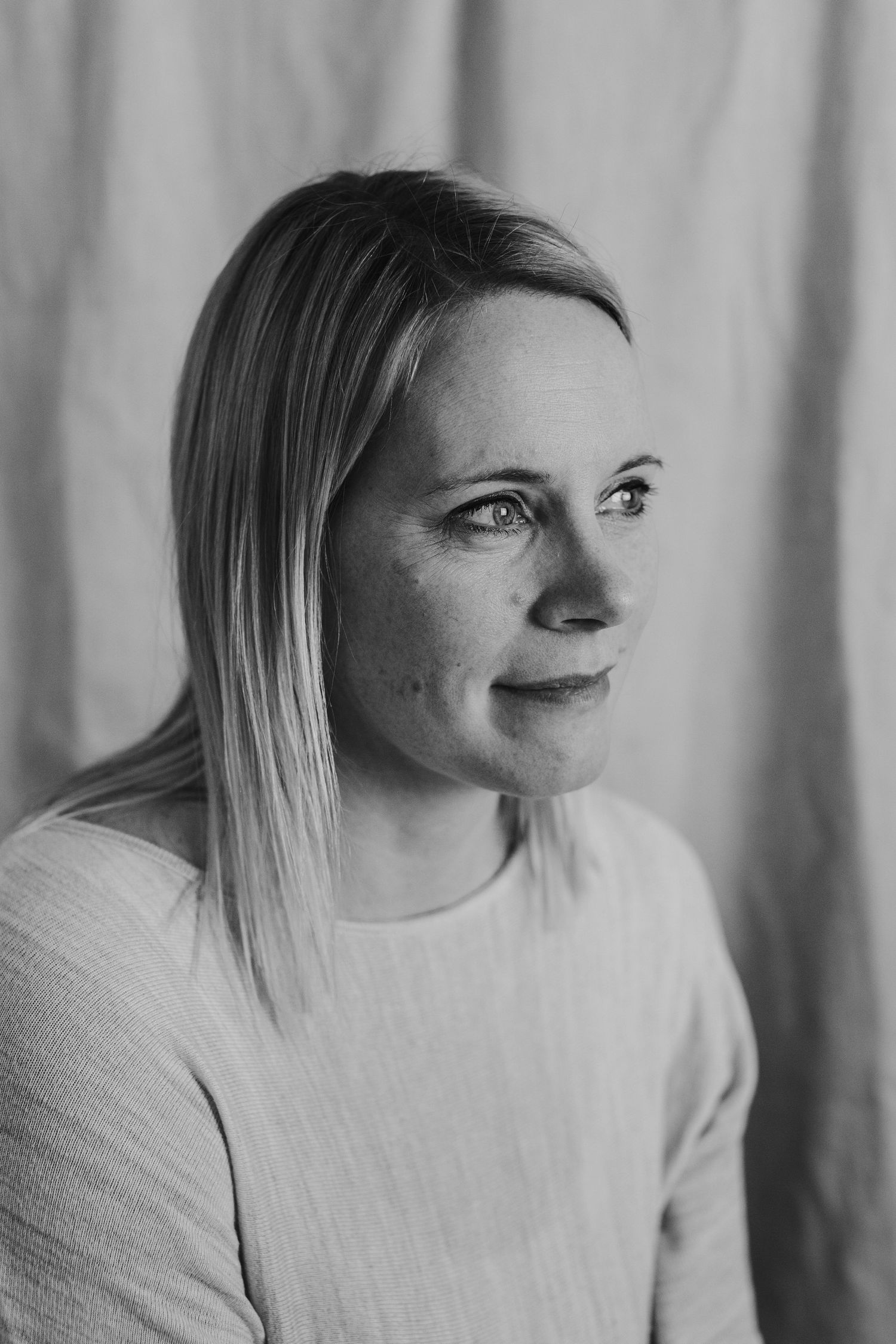 Black and white profile portrait showing gentle expression against light backdrop.