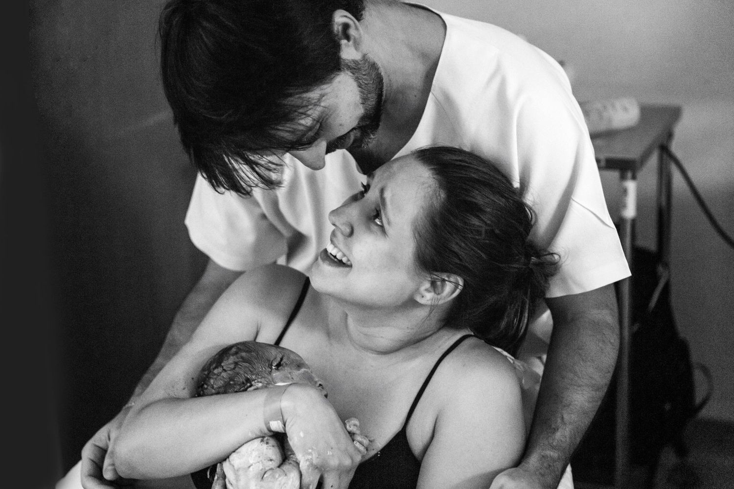 Intimate black and white photo of newborn's first moments with parents.