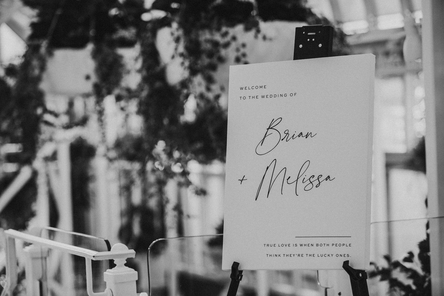 Modern minimalist black and white wedding welcome sign reading Brian and Melissa on an easel.
