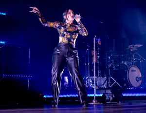 Dynamic stage performance with dramatic blue lighting and visible drum kit in background.
