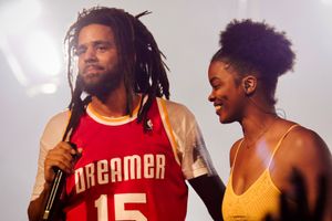 Performers on stage during a concert with one wearing a red jersey with 'Dreamer' and number 15.