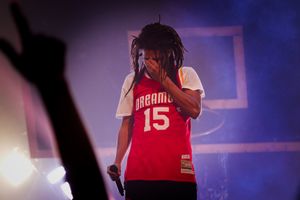 Performer wearing red jersey number 15 singing on stage with purple lighting effects.