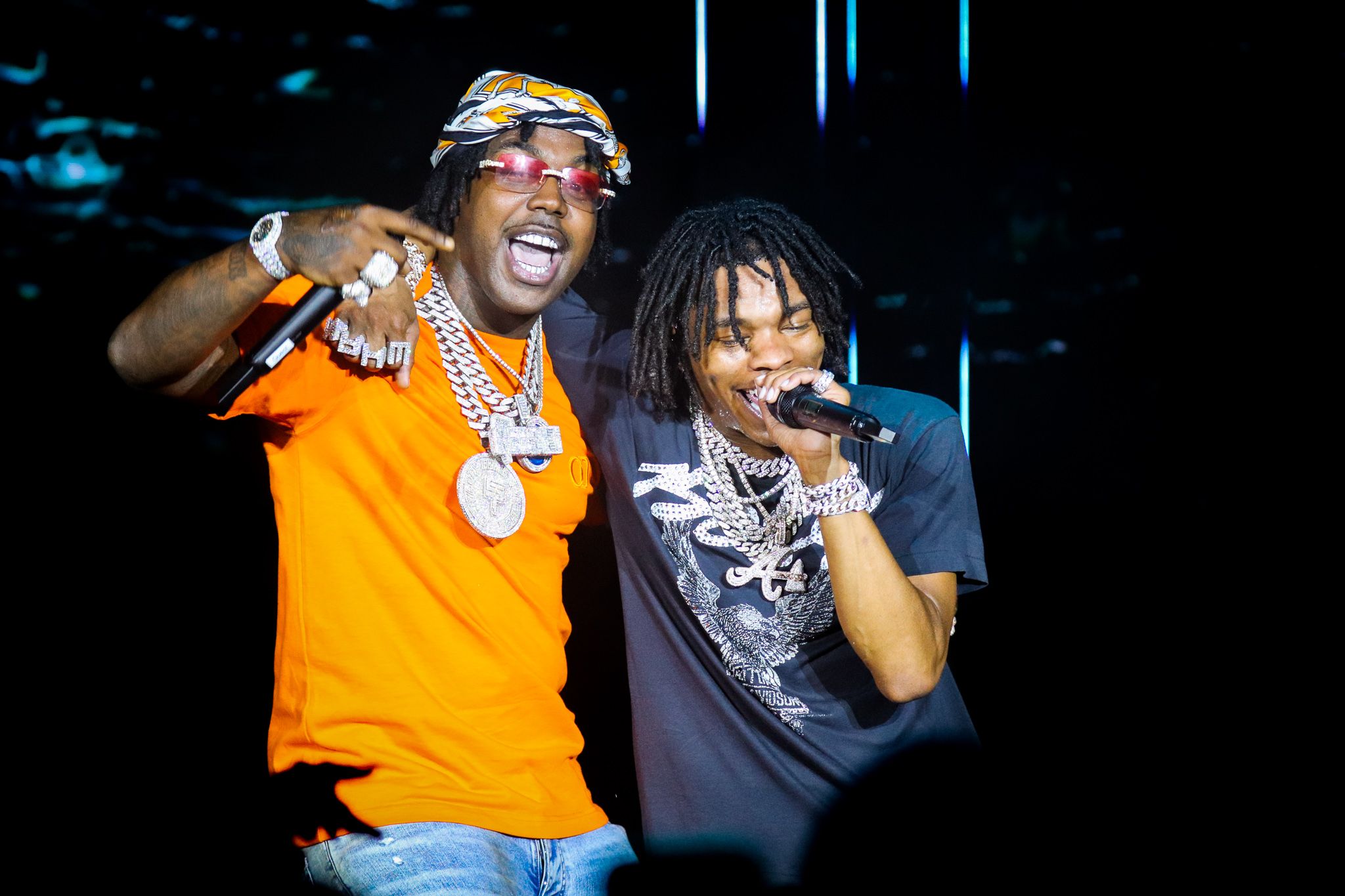 Two artists performing together on stage with blue lighting and dramatic effects.