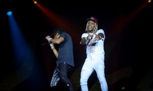Two performers on stage during concert with dramatic blue lighting effects.