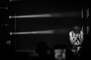 Dramatic black and white concert photo with light beams cutting through darkness.