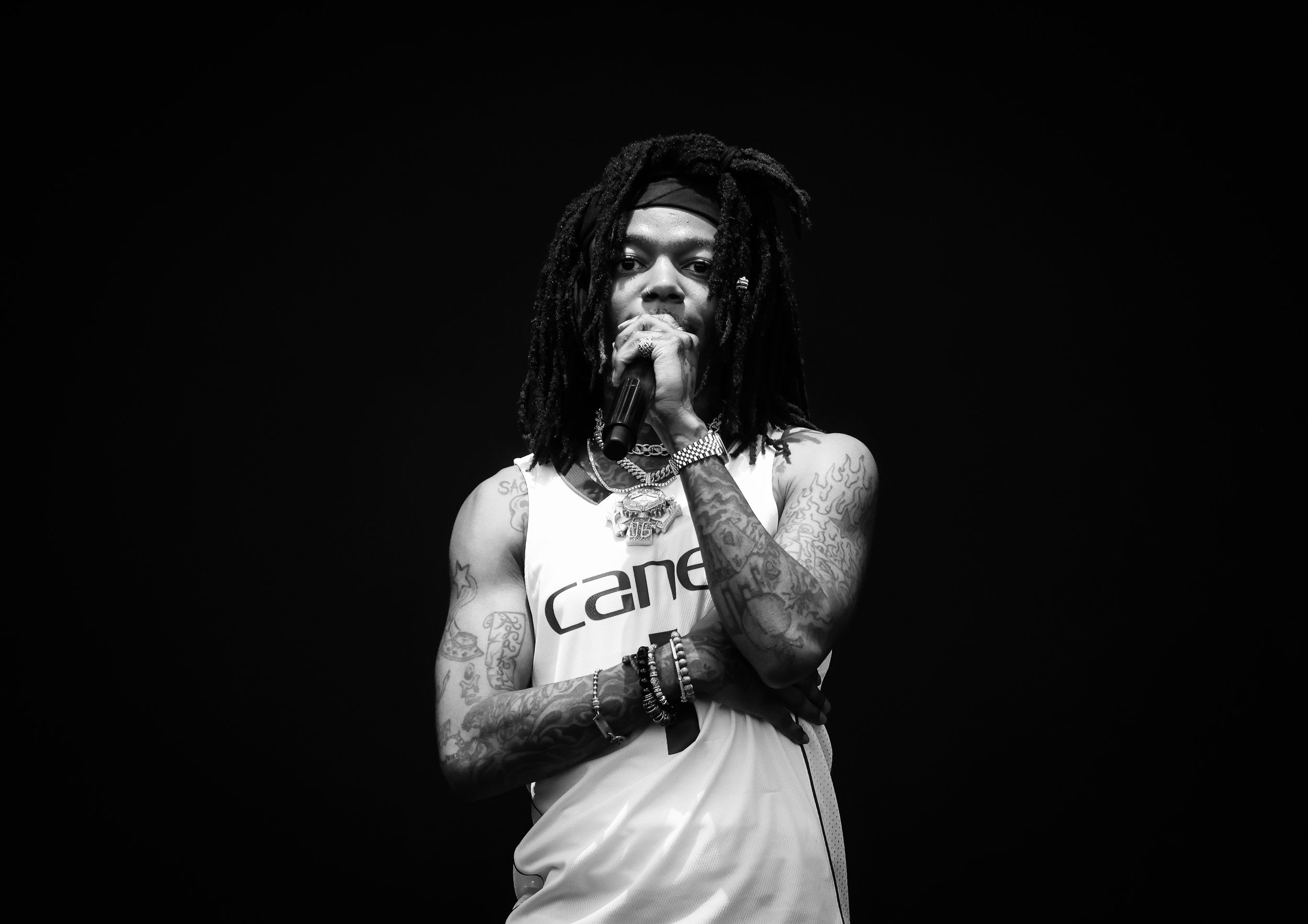 Monochrome concert photo of artist performing in white Canes tank top.