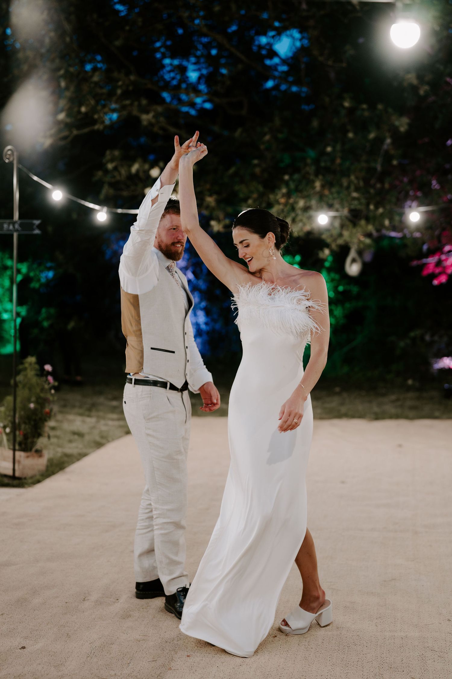 groom twirling bride surrounded by festoon lighting outside marquee in islip in oxfordshire