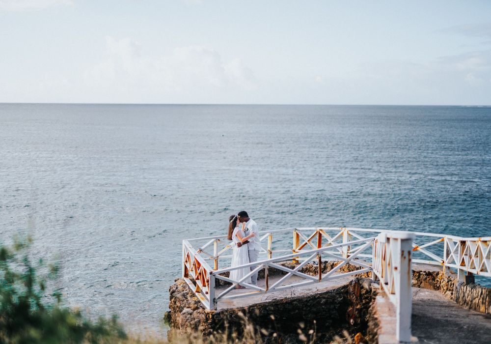A solitary figure stands on a white coastal viewing deck overlooking the ocean.