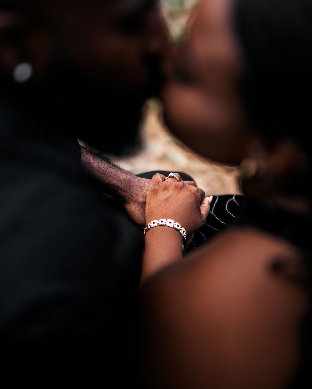 A close-up shot of clasped hands wearing a bracelet during an intimate moment.