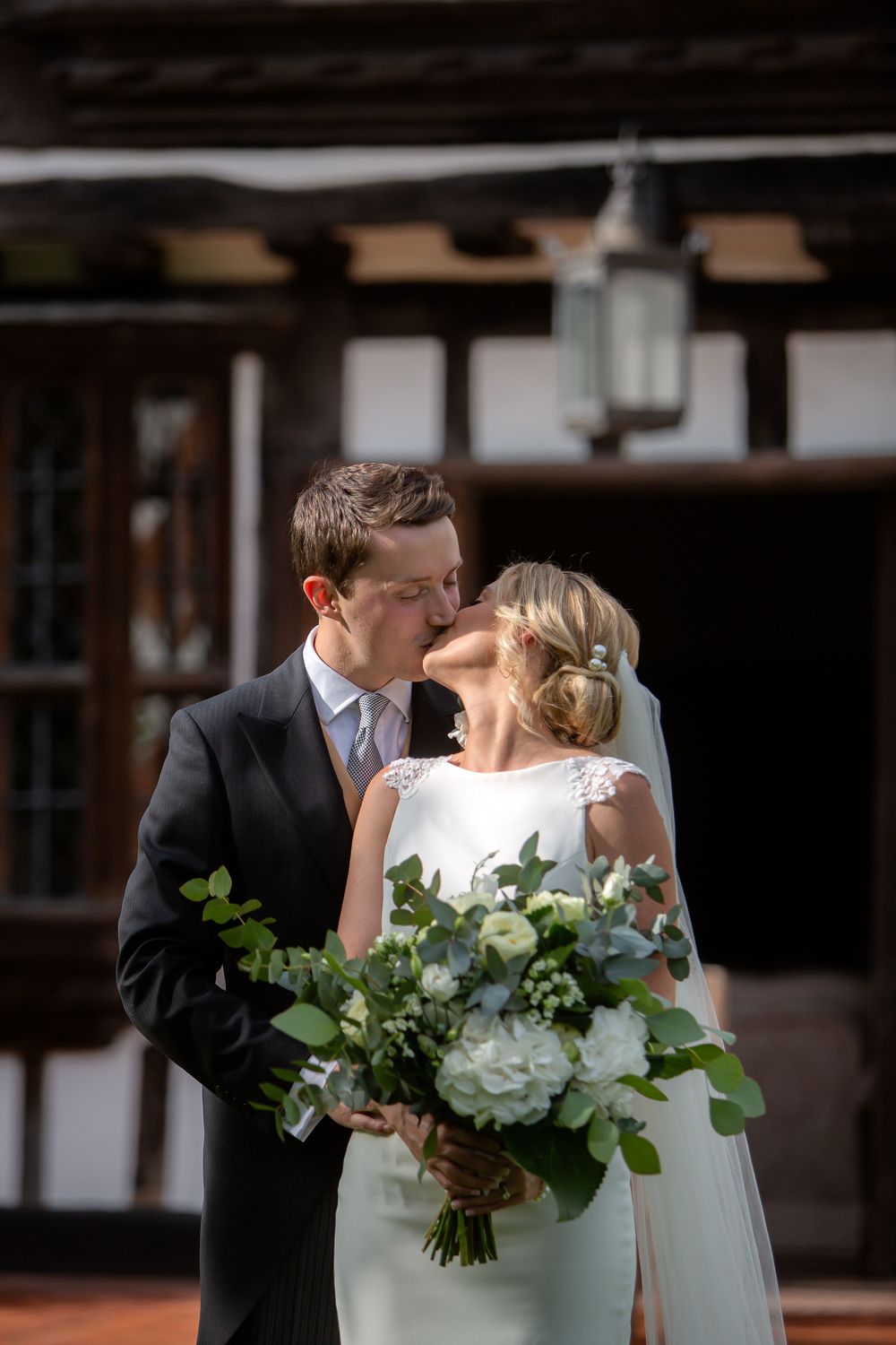 Intimate wedding portrait with bride holding white floral bouquet while sharing a tender moment.
