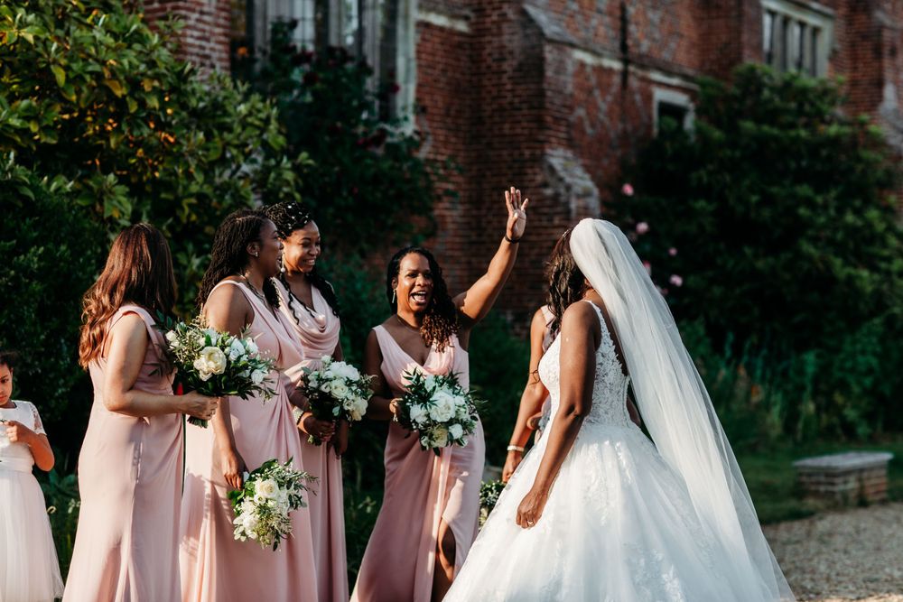 Bridesmaids in pink dresses celebrating with bride in white gown during outdoor wedding.