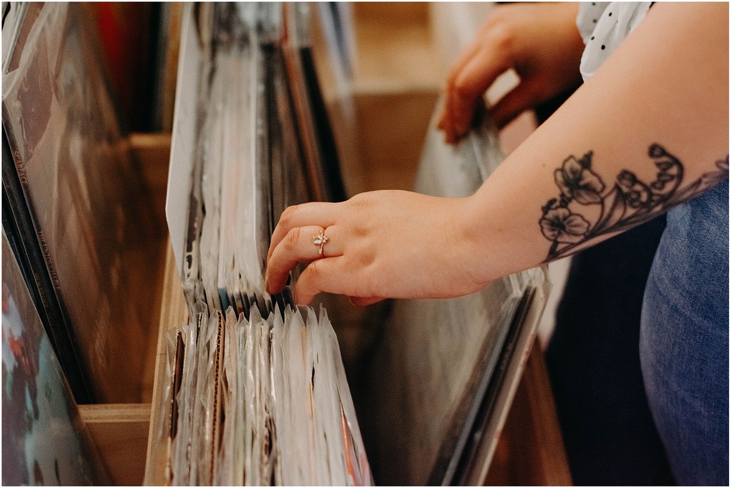 Close-up of tattooed hand browsing through vinyl records in store.