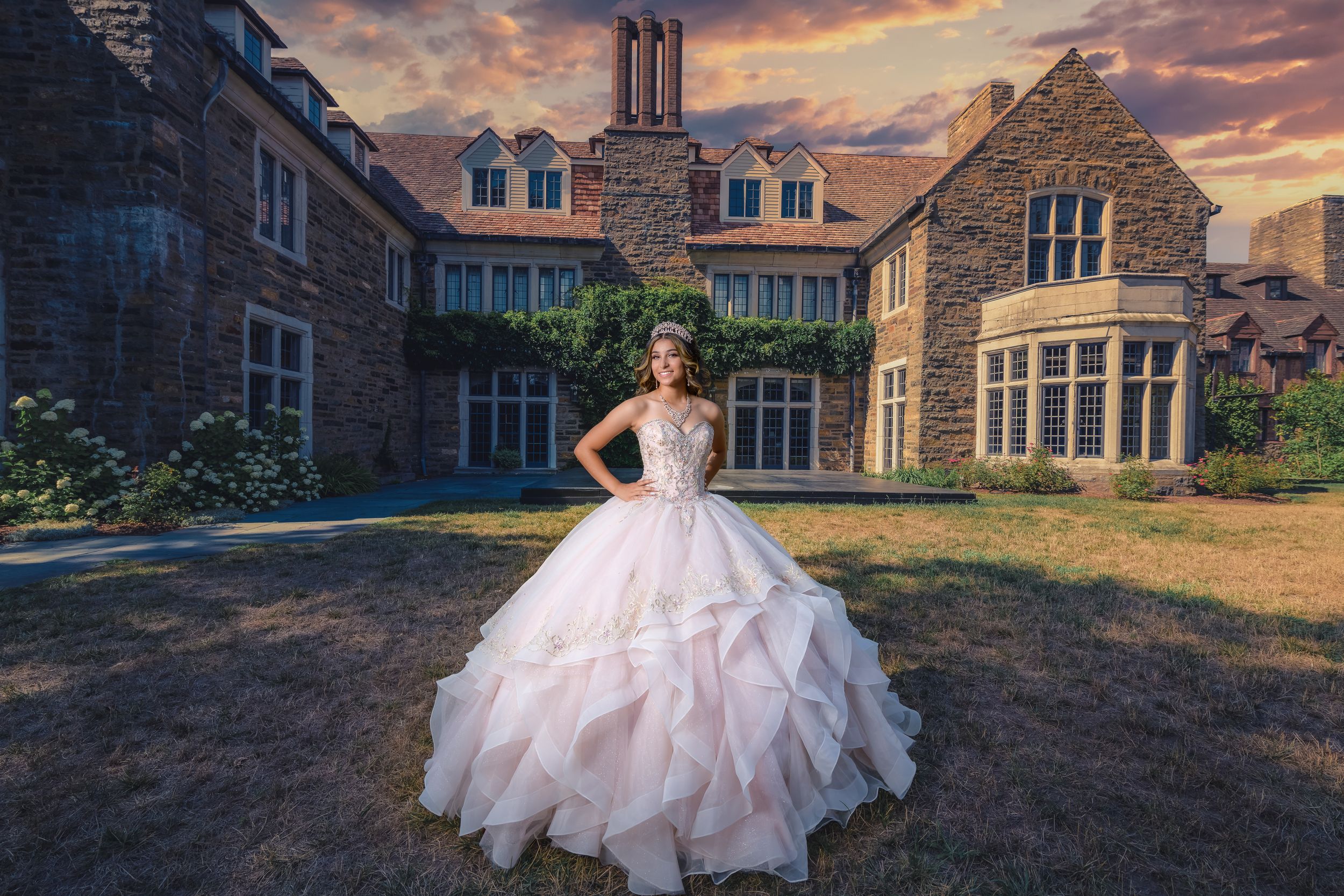 A princess-style wedding dress against a mansion backdrop during sunset.