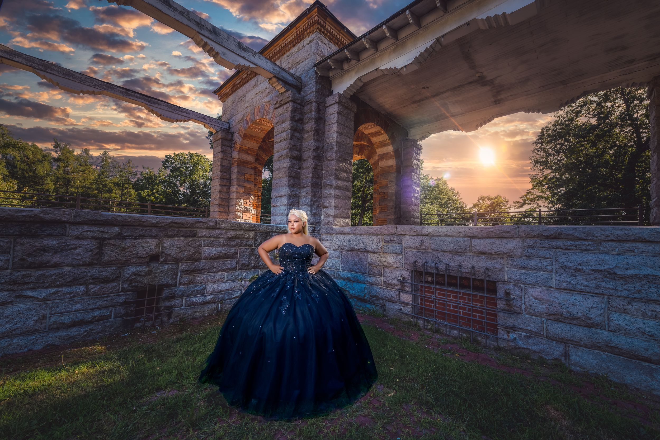 Elegant navy blue gown photographed against stone architecture at dusk.