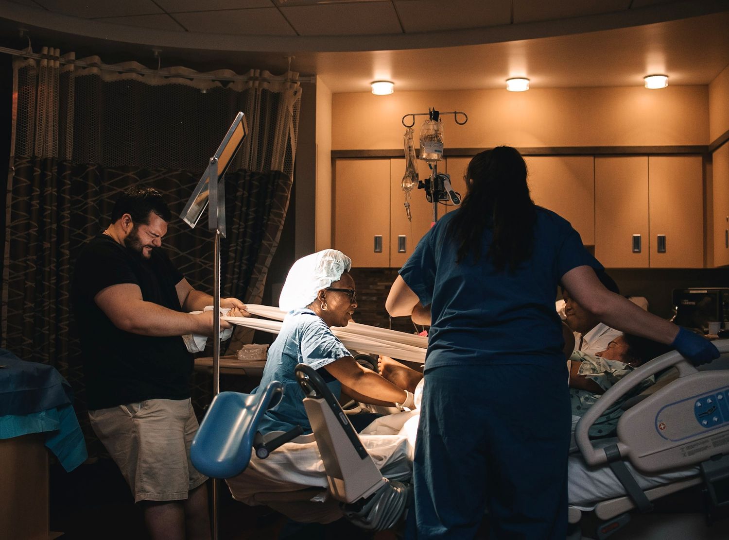 man and woman holding sheet tug of war during labor in hospital