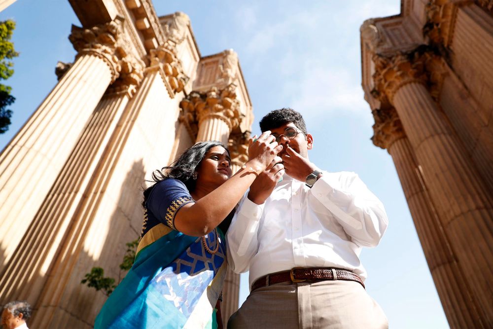 Couple shares playful moment beneath towering classical columns at Palace of Fine Arts.