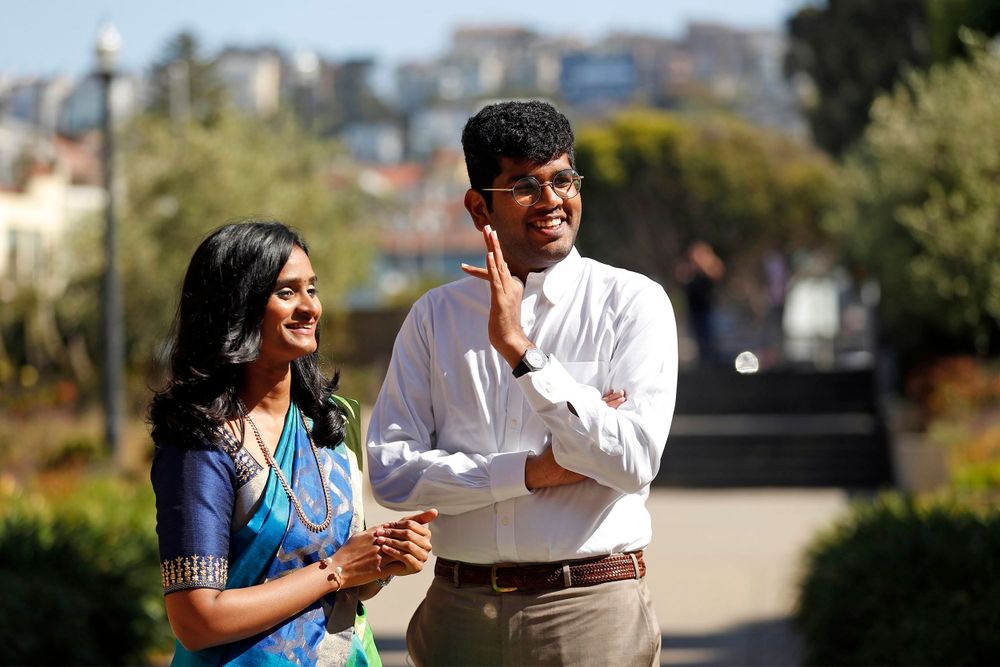 A couple sharing a joyful moment outdoors with beautiful city architecture in the background.