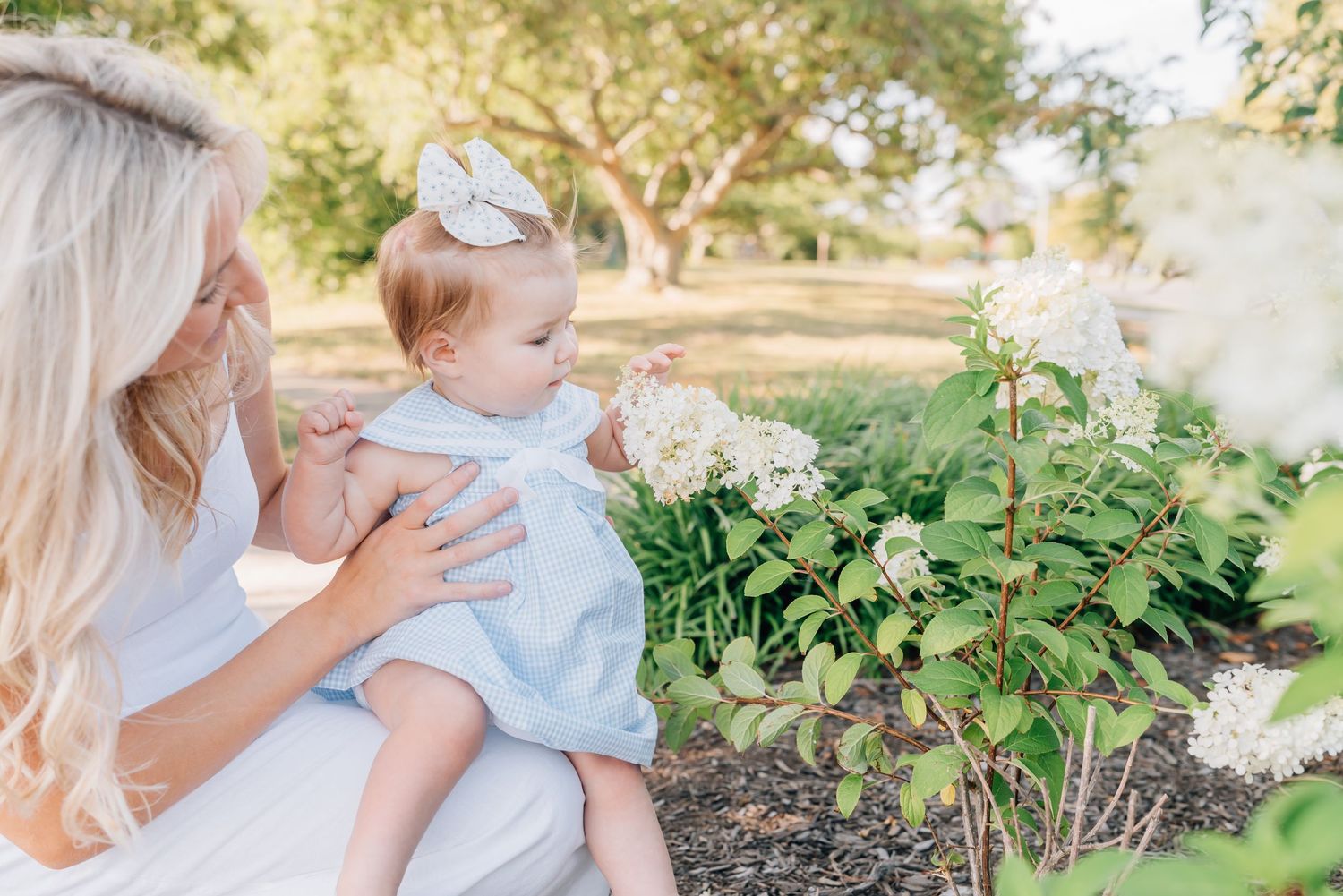 A mother holds her daughter while she plays with limelight flowers.