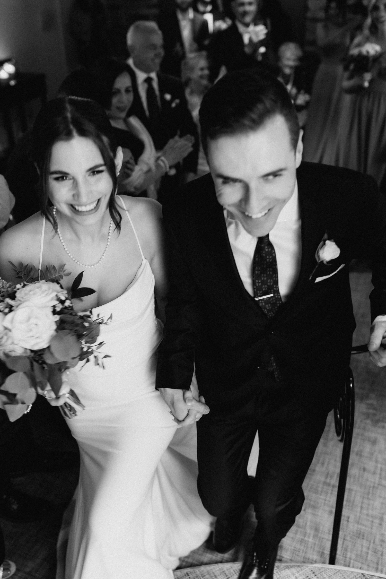 Black and white candid of newlyweds sharing a joyful moment during their reception.