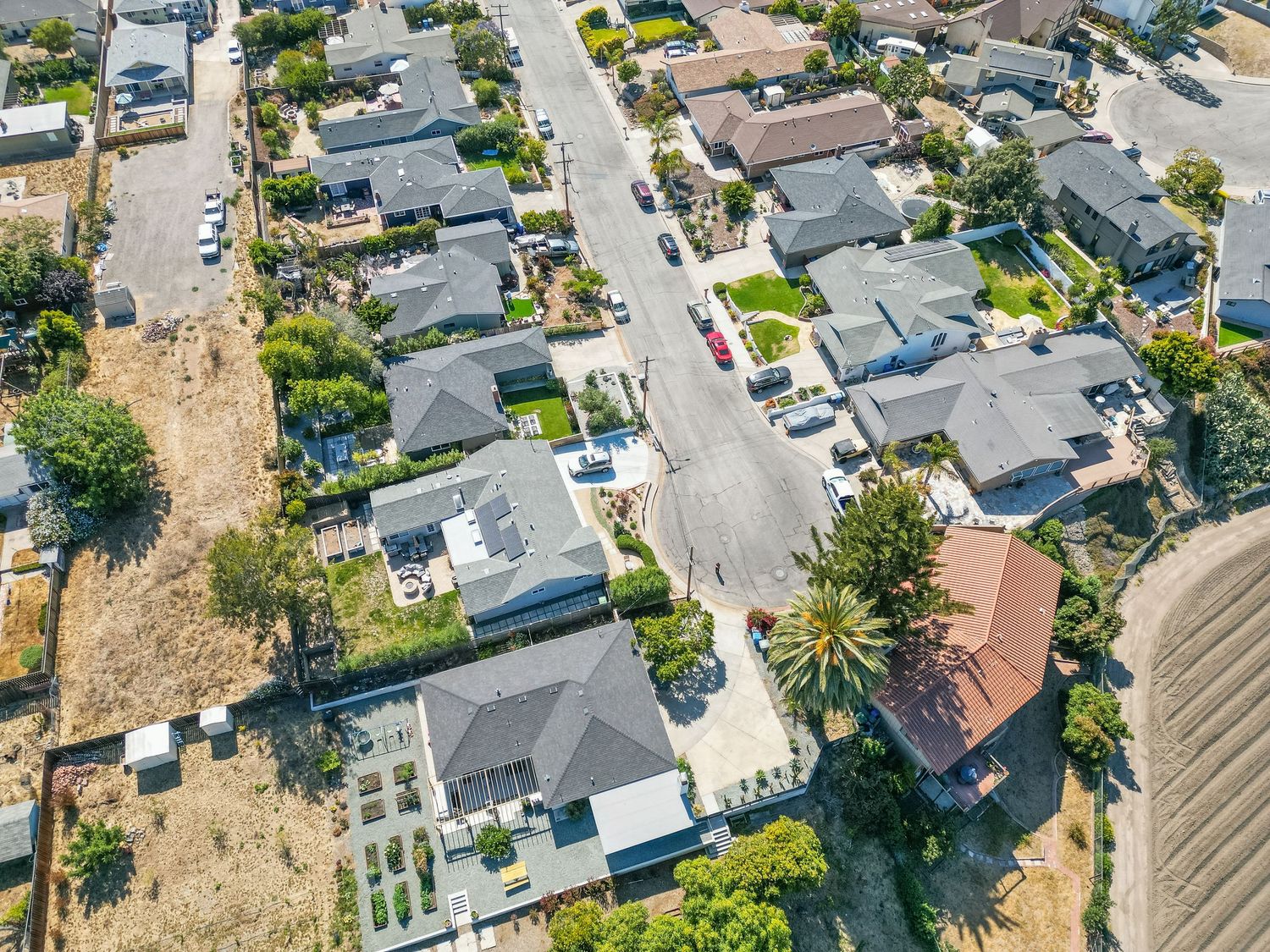 Aerial view of a residential neighborhood with houses and well-maintained yards along a suburban street.