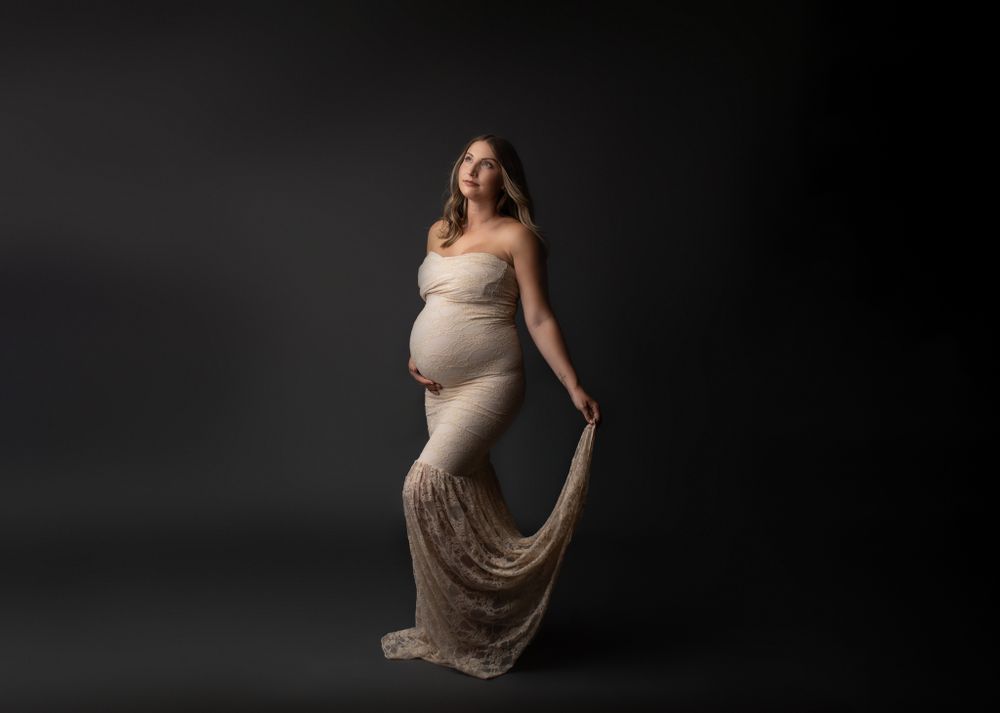 orange county maternity photographer white pregnant mother wearing champagne lace gown holding the bottom train in hand