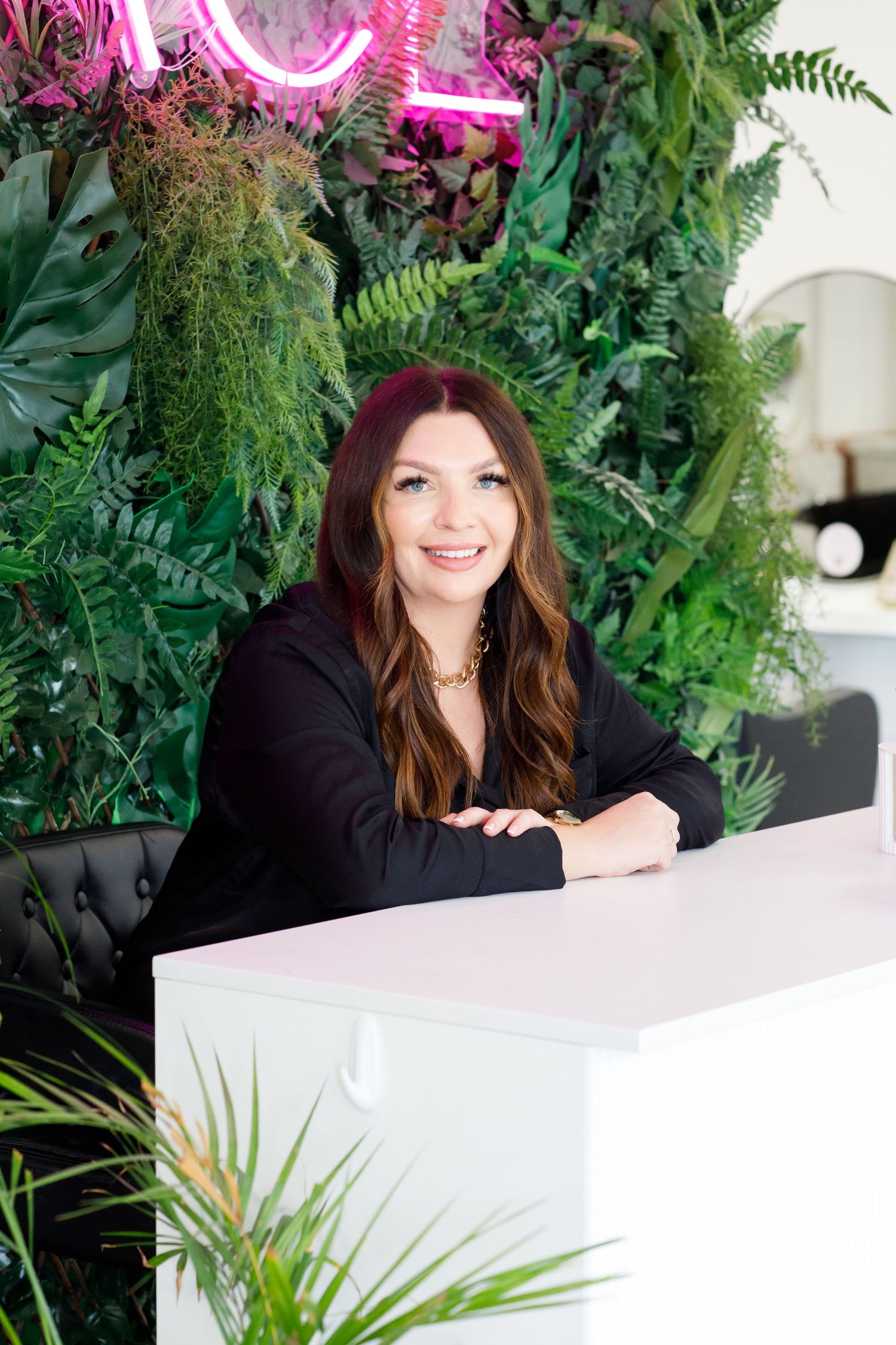 Modern beauty salon interior with lush green plant wall and neon lighting during business branding photoshoot.