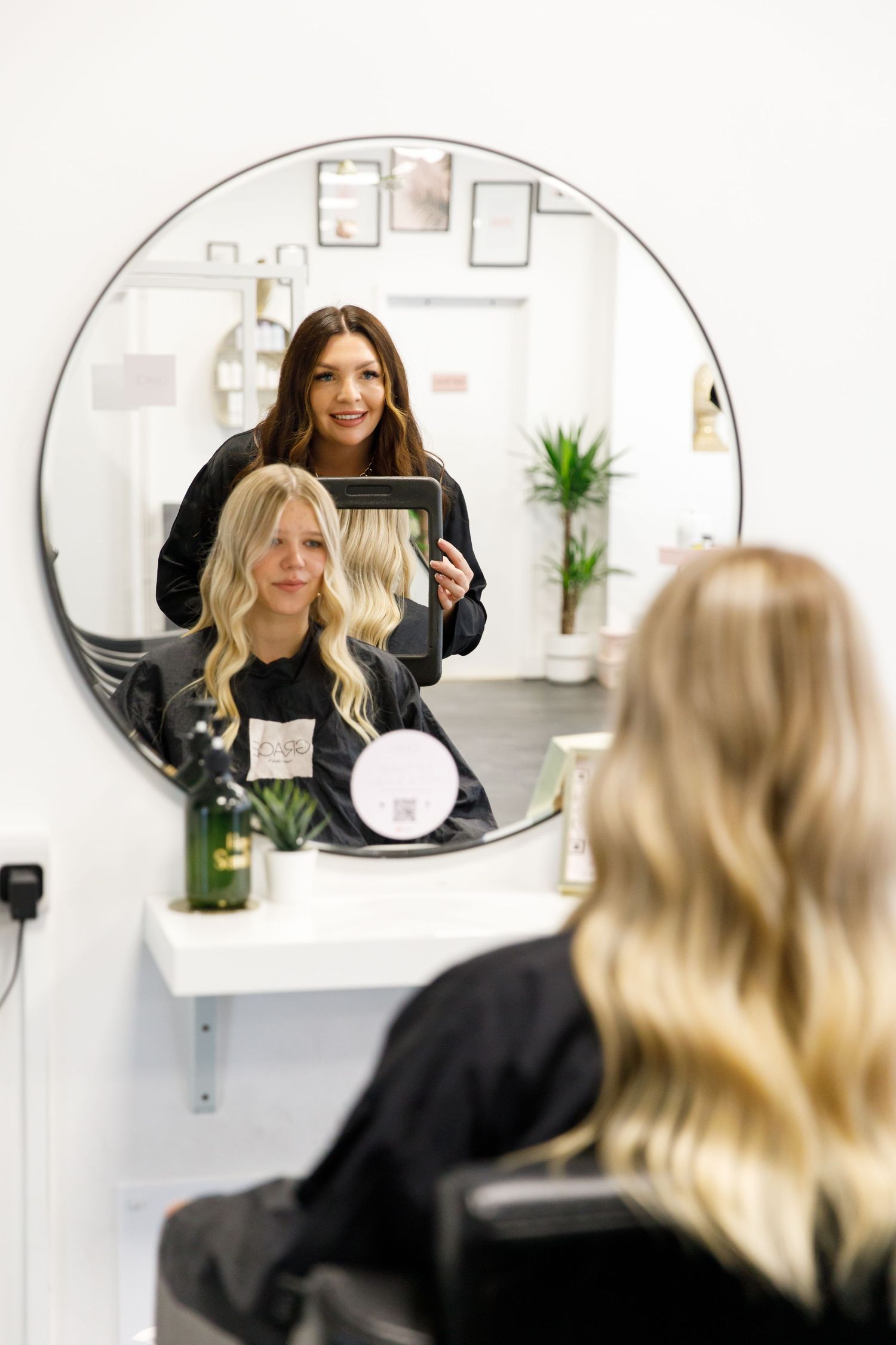 Hair styling session being reflected in a round mirror at a modern salon during business branding photoshoot.