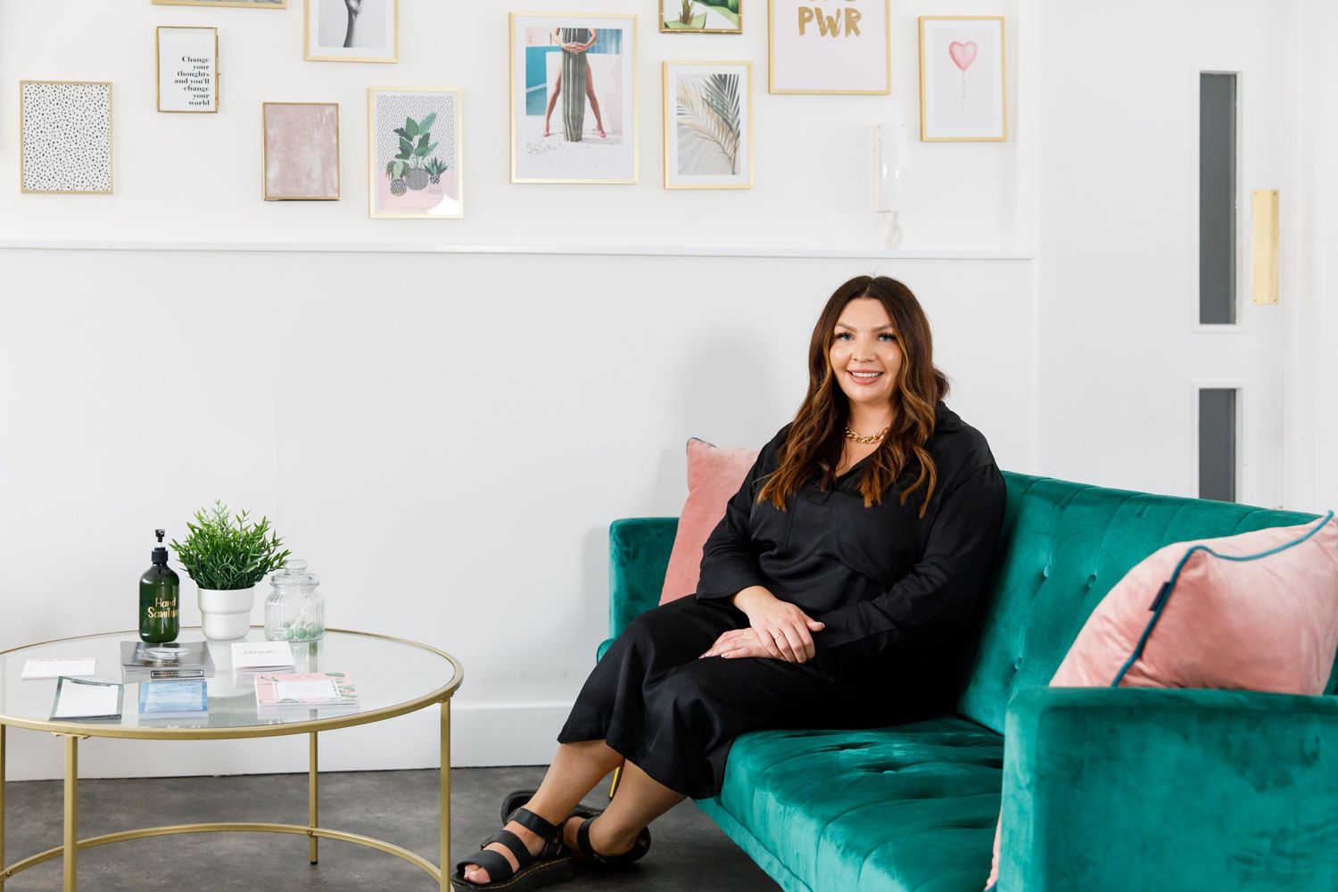 Stylish interior featuring a teal velvet sofa with pink accents and framed wall art during business branding photoshoot.