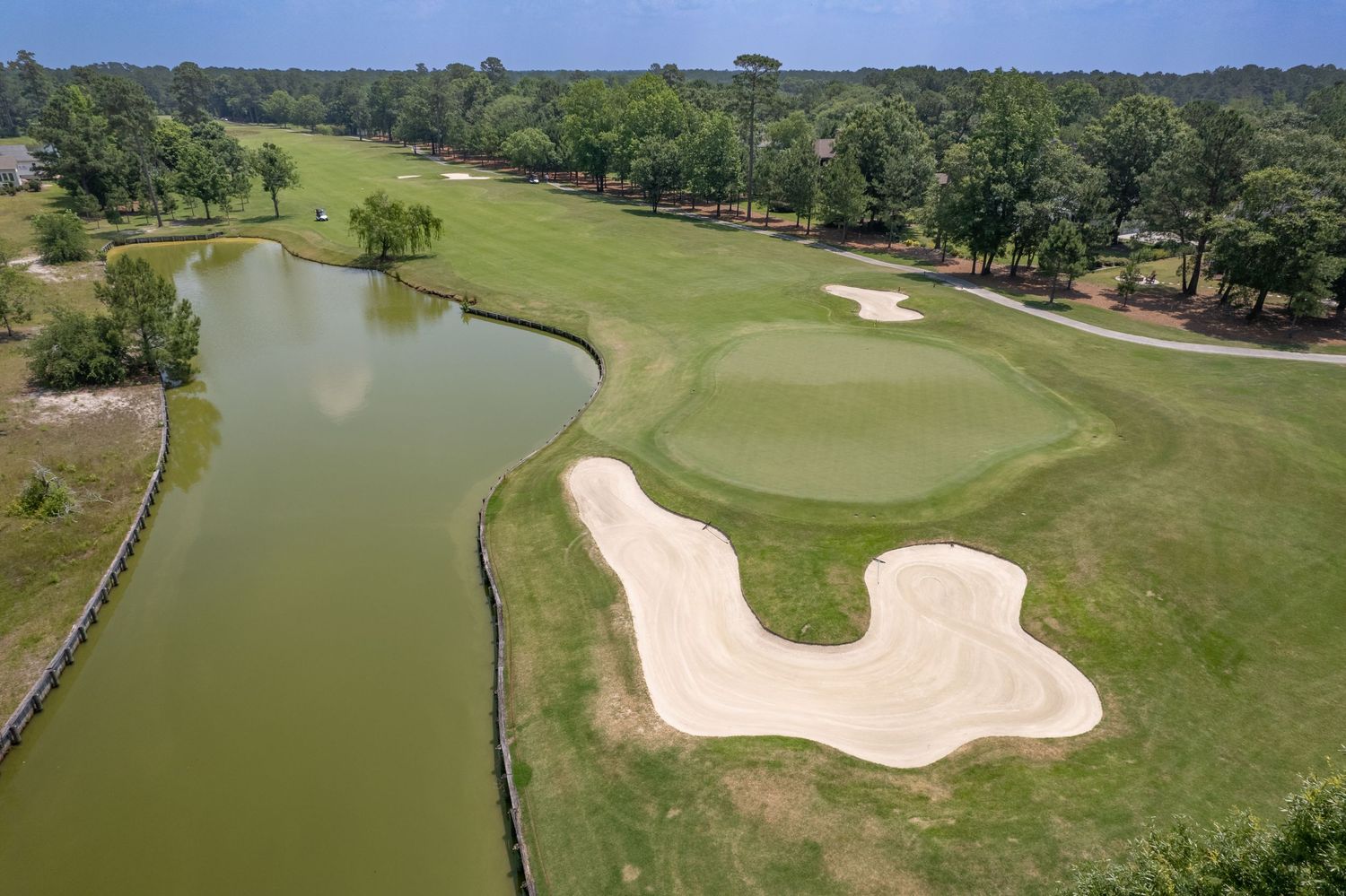 Aerial view of a lush golf course with multiple sand bunkers, water hazards, and manicured fairways stretching into the distance.