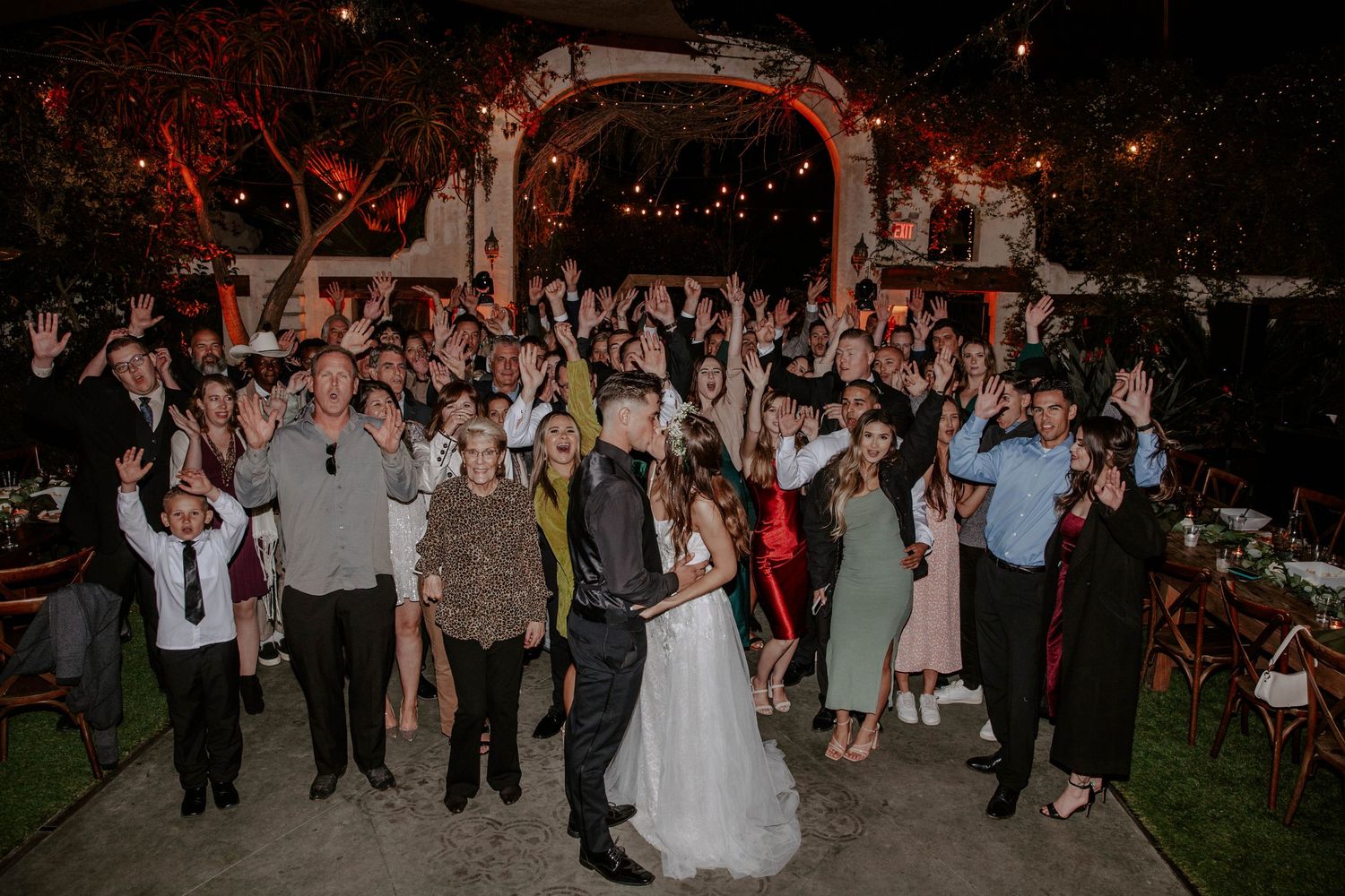 A bride and groom kiss in front of the wedding party on their wedding day.