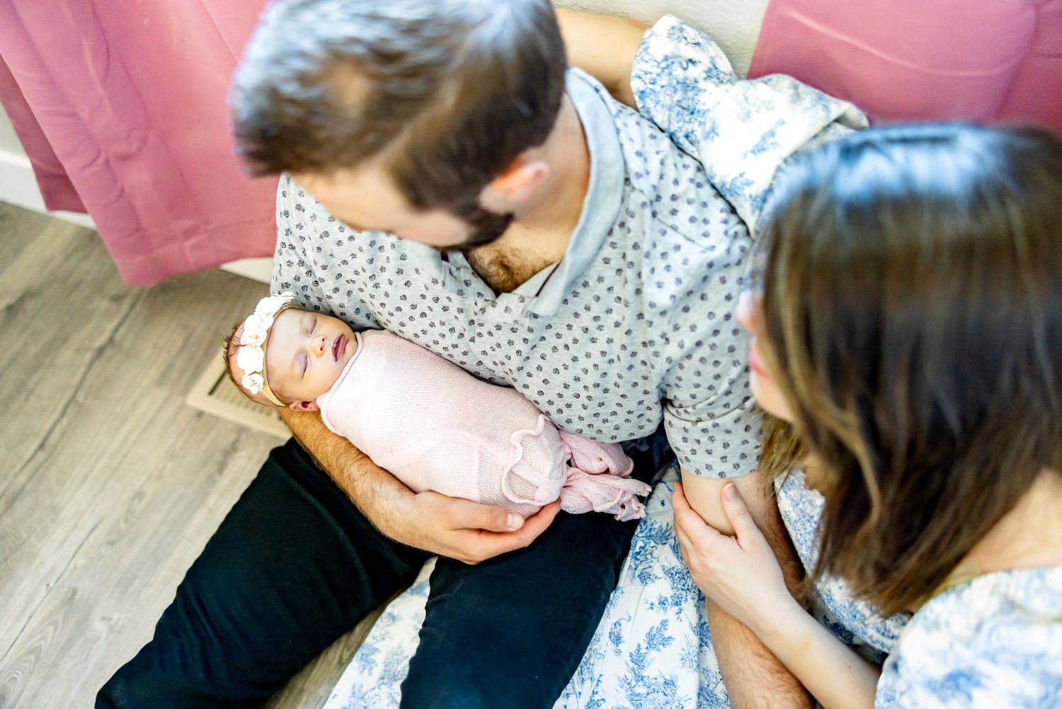 Mom and dad sit on the floor holding and looking at their new baby girl during newborn photos in Colorado Springs.
