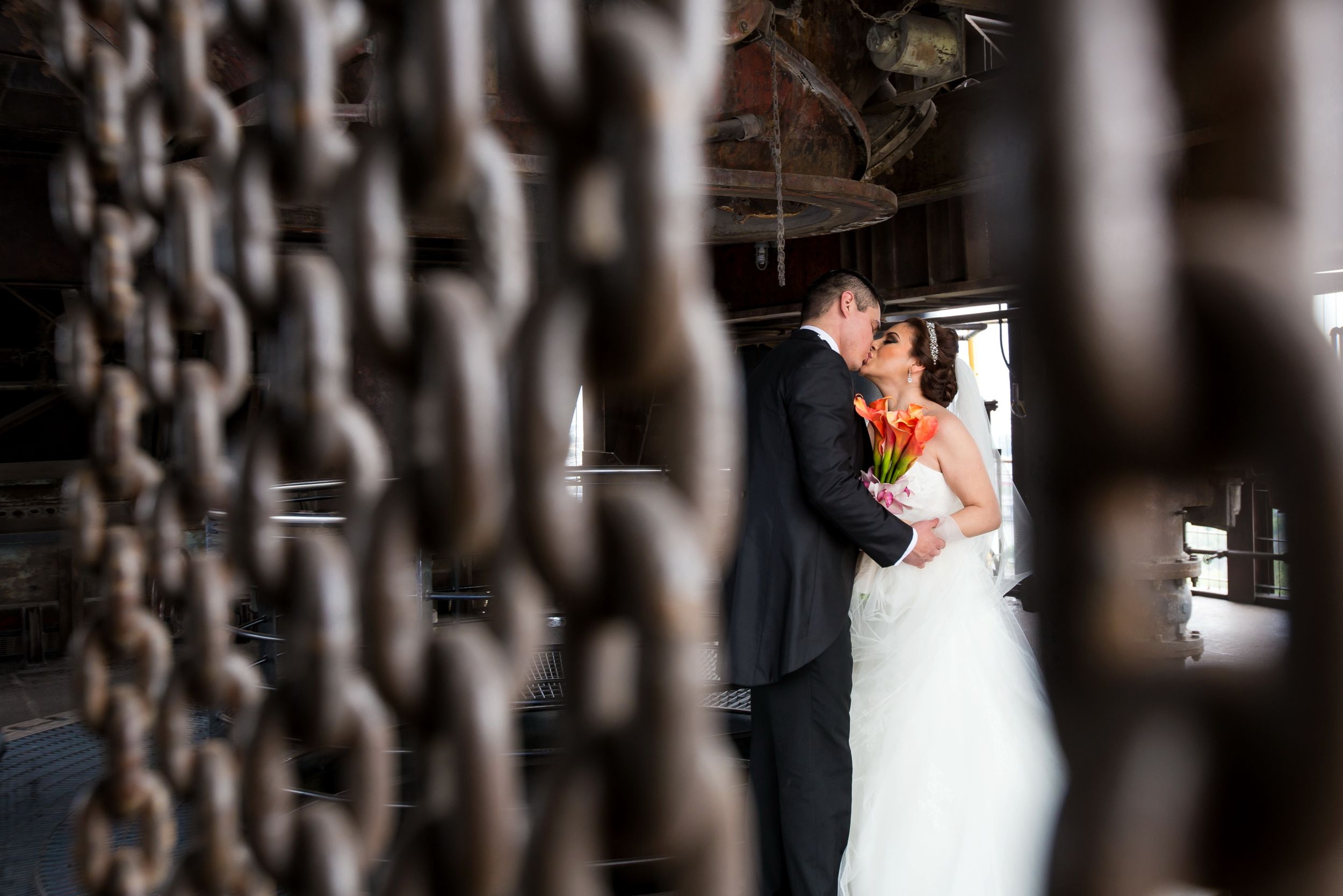 Wedding couple photographed through decorative iron gates creating an artistic framed effect.