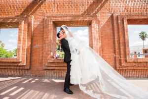 Couple poses playfully against rustic brick archways.