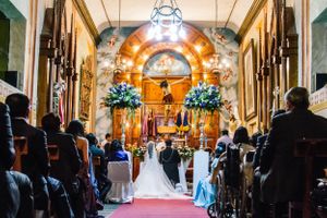A traditional church wedding ceremony in a chapel with ornate architecture and floral decorations.