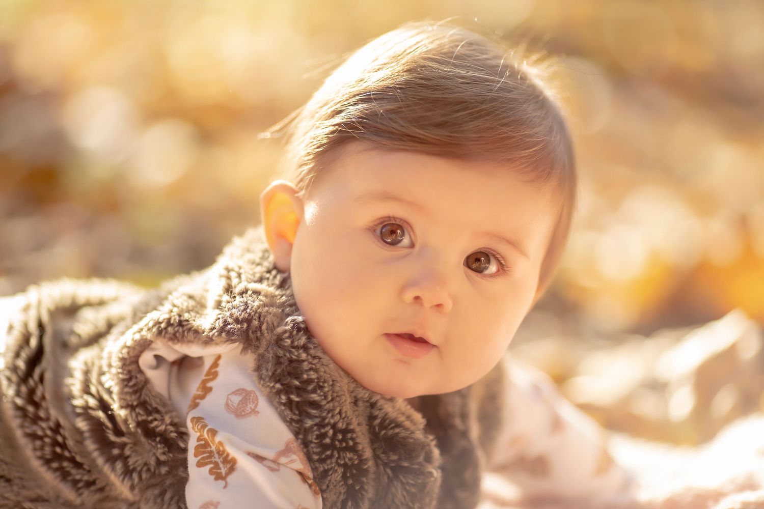 baby girl lying on her tummy out doors. Close up headshot while she looks at the camera with half smile Vancouver Family