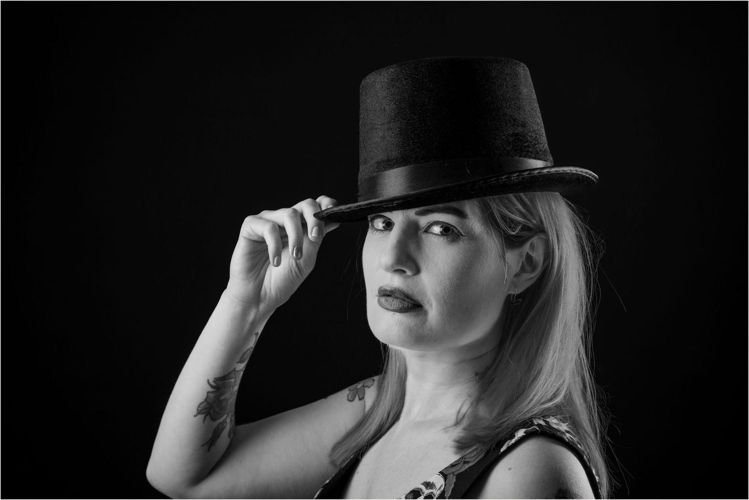 Dramatic black and white portrait with vintage top hat creating film noir aesthetic.